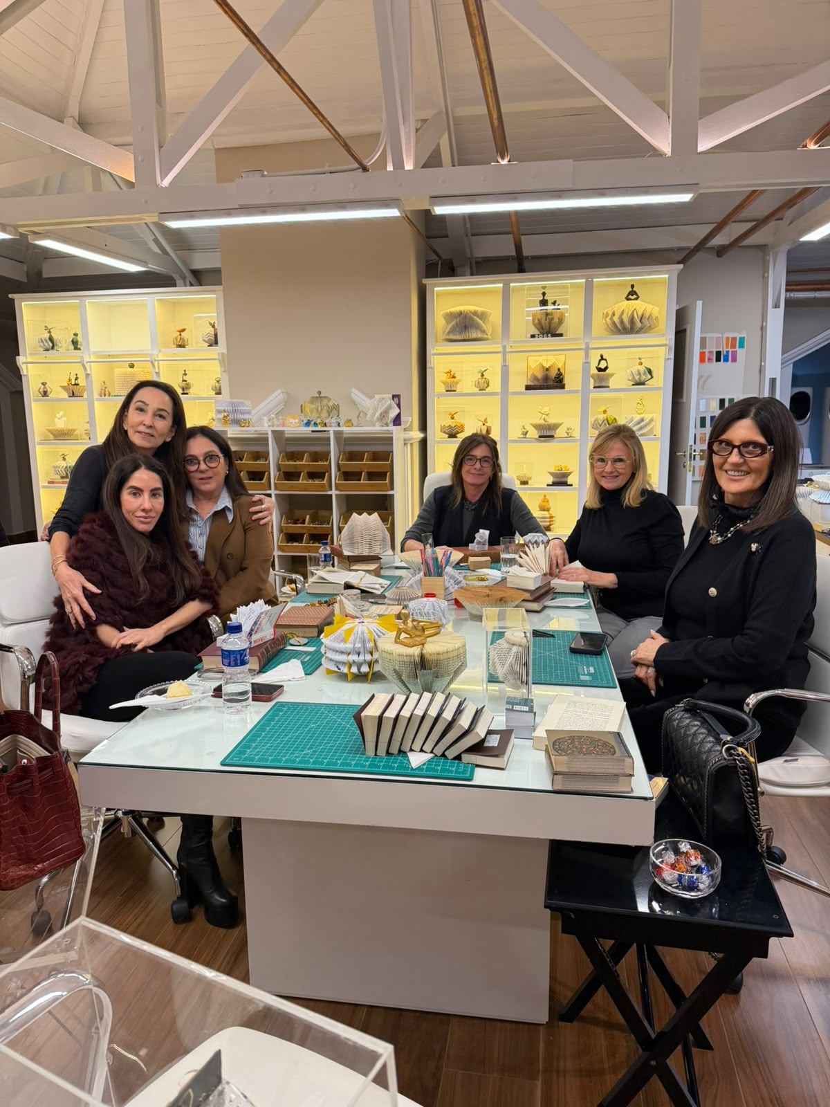 Grupo reunido em torno da mesa do ateliê, com livros e peças produzidas durante a aula